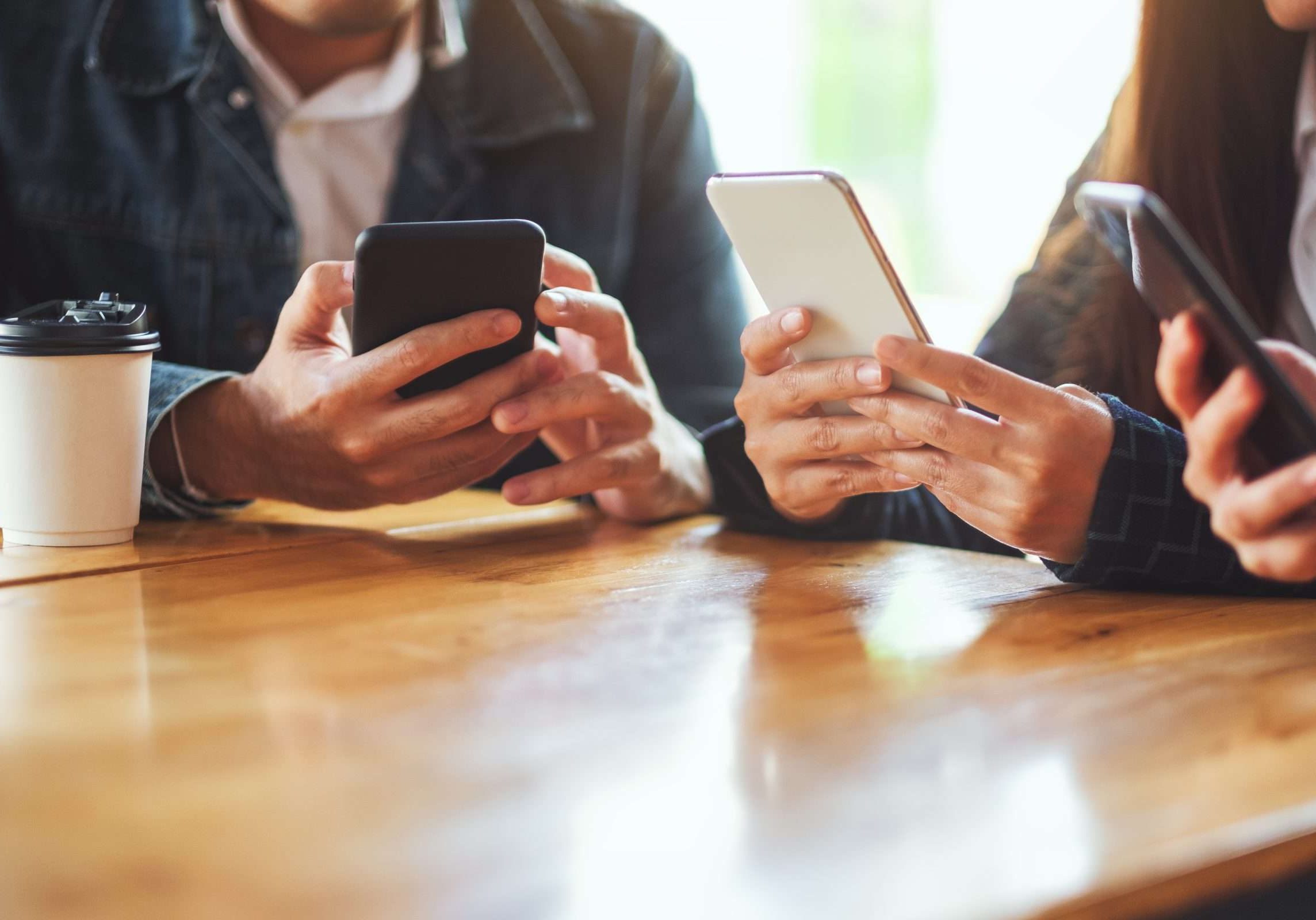 Group of people using and looking at mobile phone while sitting together